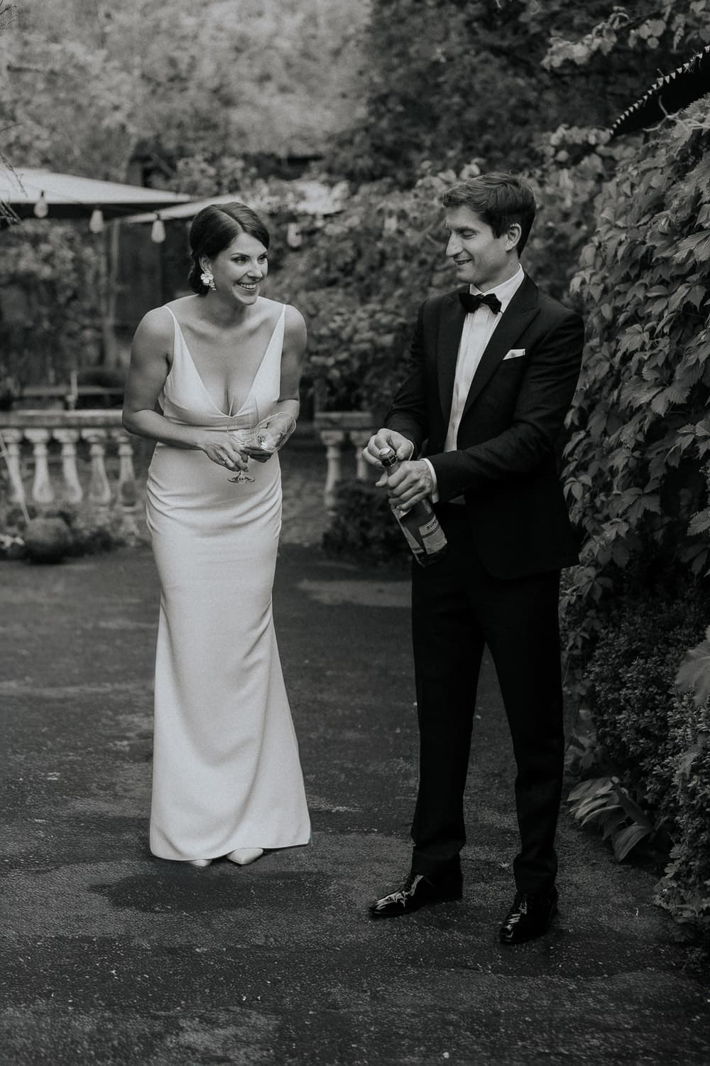 Fröhliches Brautpaar am Tag Ihrer Hochzeit während der Bräutigam gerade eine Champagner Flasche öffnet