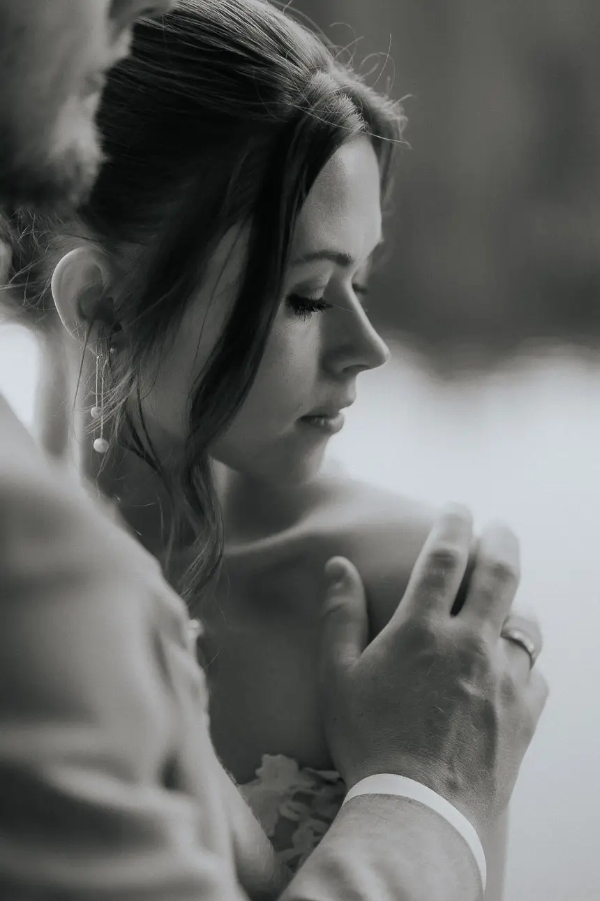 schwarz weiss Portrait Hochzeitsfoto einer Braut die vom Bräutigam zärtlich berührt wird