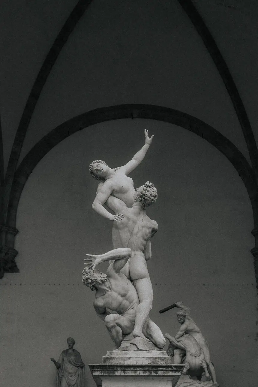 Ein schwarz weiß Foto einer antiken künstlerischen Statue mit 3 Personen