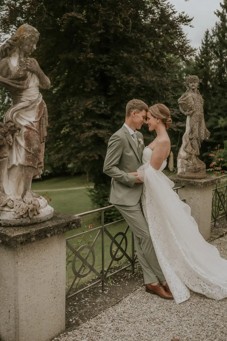 Hochzeitsfoto eines verliebten Brautpaares zwischen schönen Statuen bei der Hochzeitslocation La Villa in Starnberg bei München