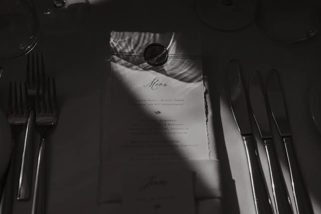Foto einer Hochzeitsmenükarte auf die sanft ein Lichtstrahl trifft